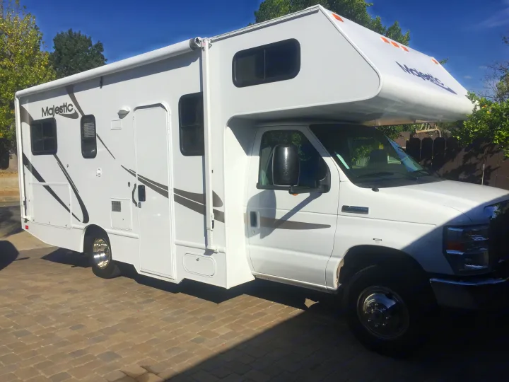 Bright white Majestic Class C RV rental shines on a paved lot under a sunny sky, ready for road trips.. Ford Majestic 23A 2012