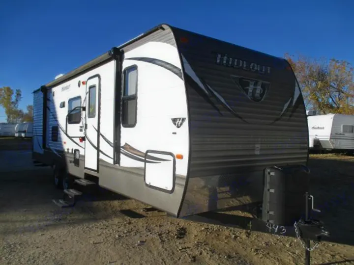 Explore in this Hideout travel trailer! A white and gray RV rental, parked under a clear blue sky.. Keystone Hideout 2014