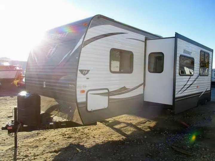 Large gray & white travel trailer RV with slide-out extended, parked outdoors. Great for your next rv rental adventure.. Keystone Hideout 2014
