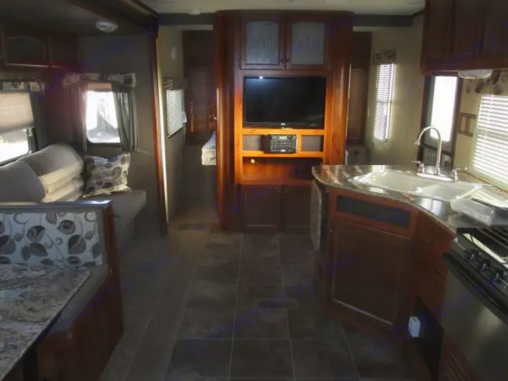 Inside an RV rental, showing a modern kitchen, living area with sofa, and entertainment center, ready for adventure.. Keystone Hideout 2014