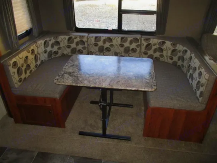 U-shaped dinette with a stone-look table in an RV rental. Features patterned cushions and built-in storage.. Keystone Hideout 2014