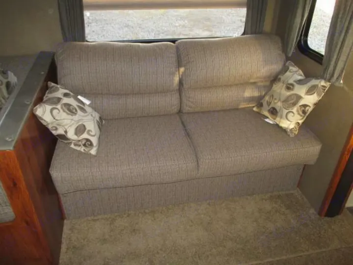 Cozy RV rental interior with a comfortable sofa, two patterned pillows, and carpeted floor, ideal for travel.. Keystone Hideout 2014