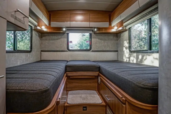 Cozy rv rental interior with comfortable beds, wooden cabinetry, and bright windows, offering a peaceful sleeping area.. Winnebago View 2016