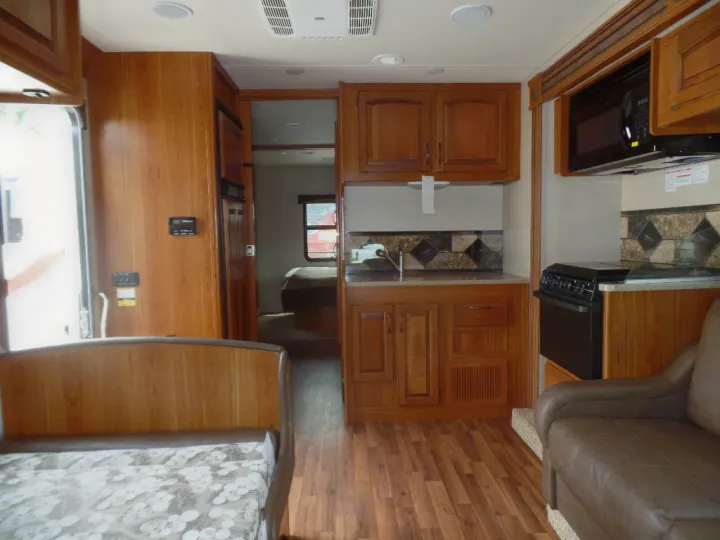 Inside this comfortable rv rental: a well-appointed kitchen, living area with bed, and rich wood cabinetry detail.. Jayco Greyhawk 2016