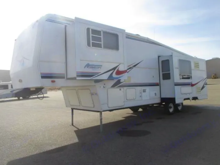 A white fifth-wheel recreational vehicle (RV) with slide-outs extended, parked on asphalt. Ideal for your next RV rental adventure.. Holiday Rambler Alumascape 2002