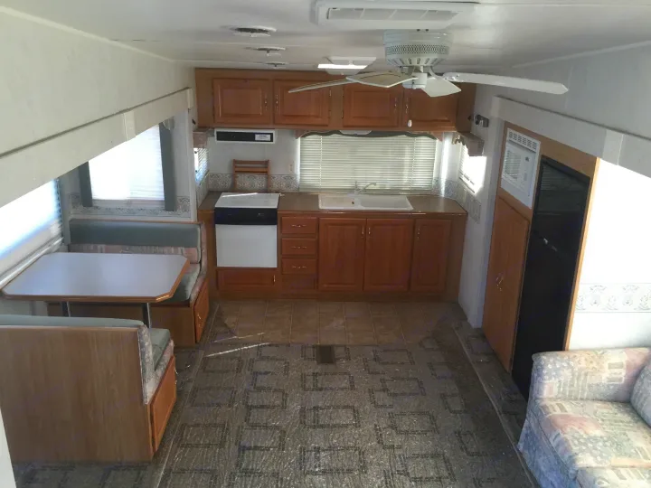 Spacious RV rental interior featuring a full kitchen, dining booth, and living area, ready for your next adventure.. Holiday Rambler Alumascape 2002