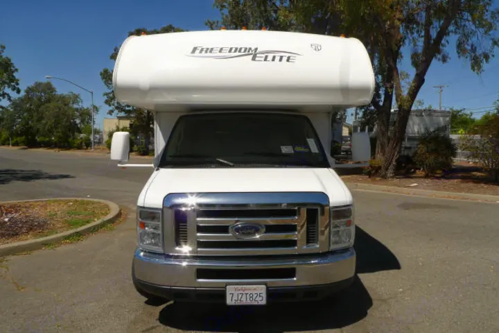 Front view of a white "Freedom Elite" Class C RV rental, showcasing its prominent Ford grille and chrome bumper.. Forest River Freedom 2013