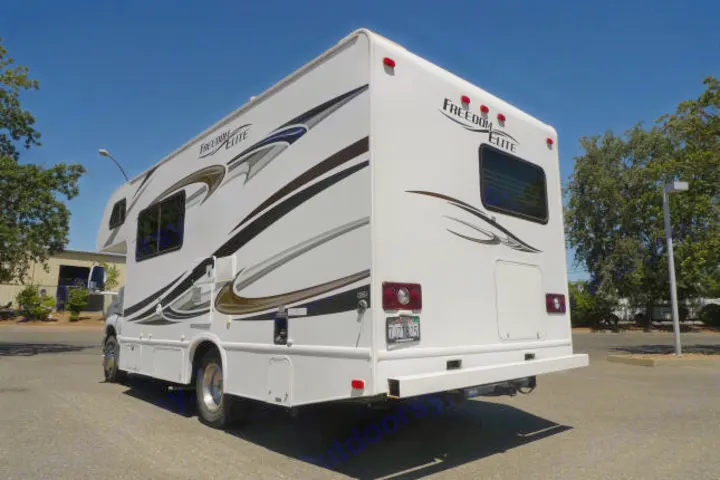 White "Freedom Elite" RV rental, a spacious motorhome ready for your next adventure. Side/rear view.. Forest River Freedom 2013