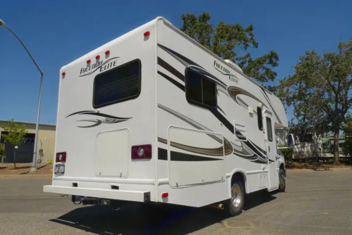 White Freedom Elite Class C RV rental, sporting stylish graphics, parked outdoors on a sunny day for travel.. Forest River Freedom 2013
