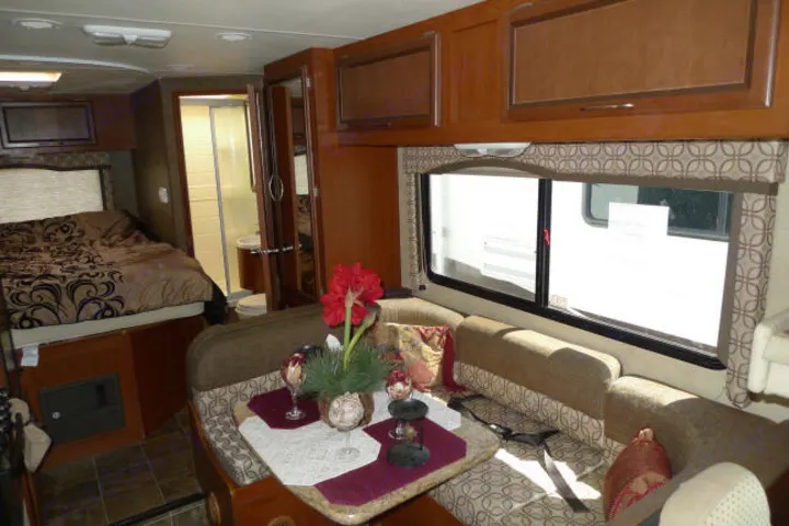 Step inside this RV rental, featuring a comfortable bedroom, full bathroom, and a spacious dining area with large windows.. Forest River Freedom 2013