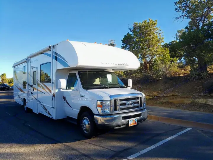This white Chateau Class C **rv rental** is parked on asphalt with trees in the background, ready for your next outdoor adventure.. Thor Motor Coach Chateau 2011