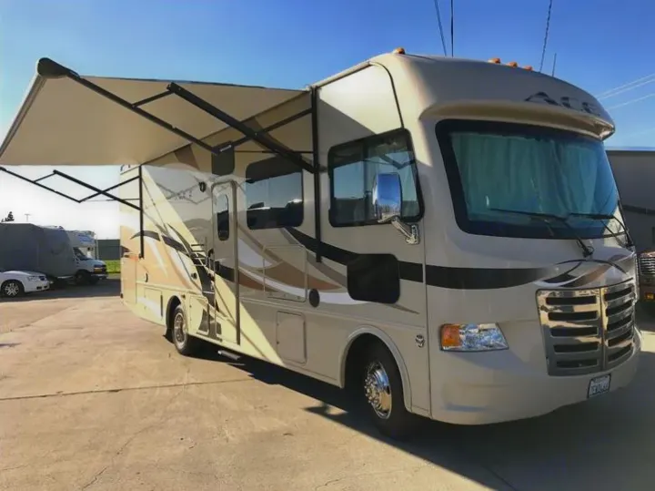 Spacious cream Class A motorhome rv rental with extended awning, parked outdoors. See its full exterior.. THOR A.C.E 30.2 2015