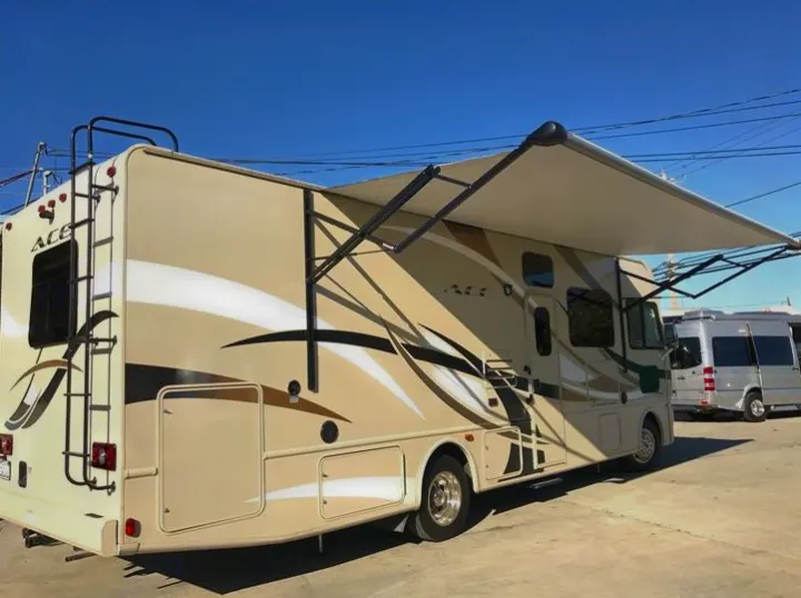Spacious beige ACE RV rental with an extended awning, perfect for road trips and outdoor fun.. THOR A.C.E 30.2 2015