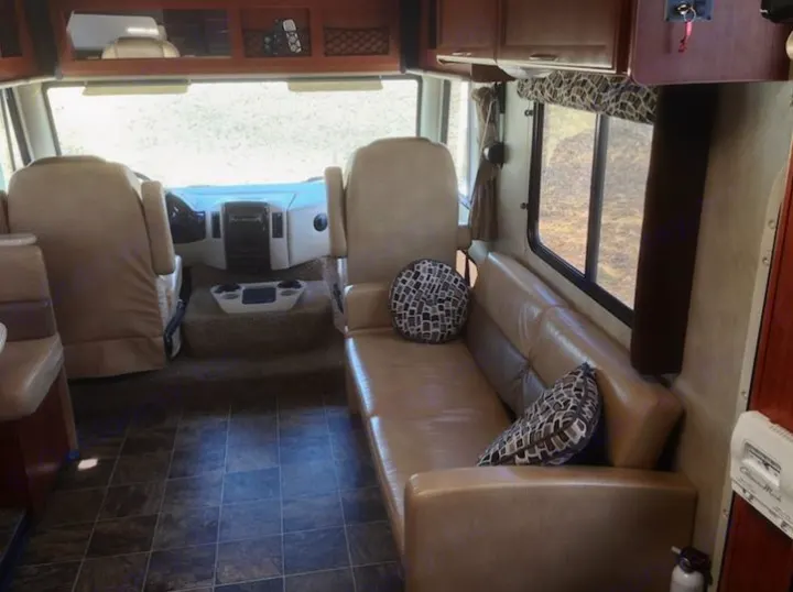 Inside a comfortable RV rental: living area with sofa, cockpit, and tiled floor, ready for your road trip adventure.. THOR A.C.E. 29.1 2012