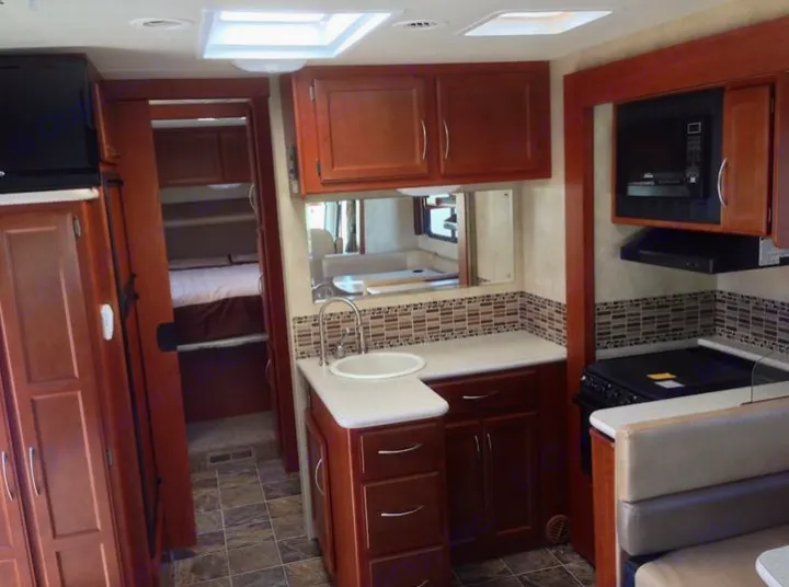 RV rental: Functional interior with compact kitchen (sink, stove, microwave), reflected dining, and bedroom with bunk beds.. THOR A.C.E. 29.1 2012