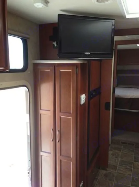 Experience an RV rental: Interior showing a TV entertainment center, wood cabinets, and access to the bunk area.. THOR A.C.E. 29.1 2012