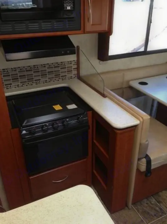 RV rental interior: kitchen featuring oven, microwave, backsplash, and a cozy dinette with booth seating.. THOR A.C.E. 29.1 2012