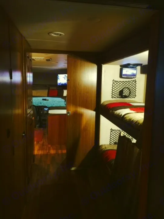 Cozy RV rental interior: bunk beds with TVs, wood flooring, and a spacious living area visible beyond.. Jayco Greyhawk 2016
