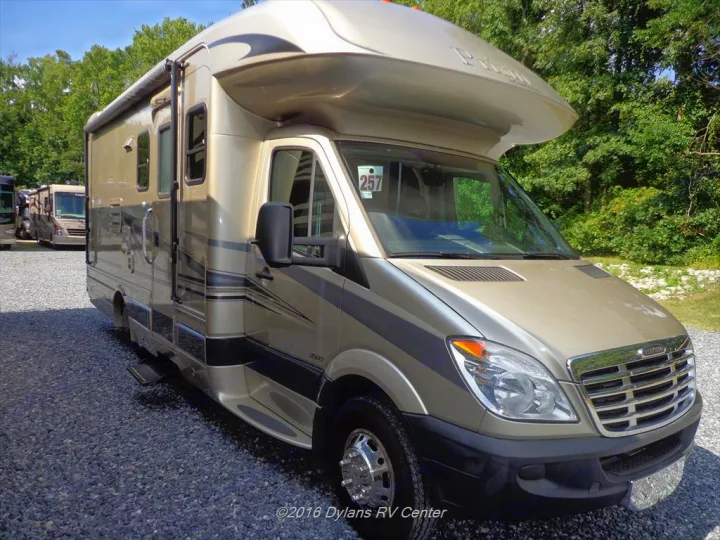 Tan Prism Class C RV rental on a gravel lot. This compact motorhome offers versatile travel options.. Coachmen Prism 2009