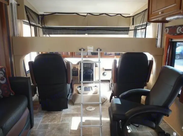 RV rental: Spacious interior showing cockpit, swivel chairs, and an overhead bunk with ladder.. Thor Motor Coach OutLaw 2015