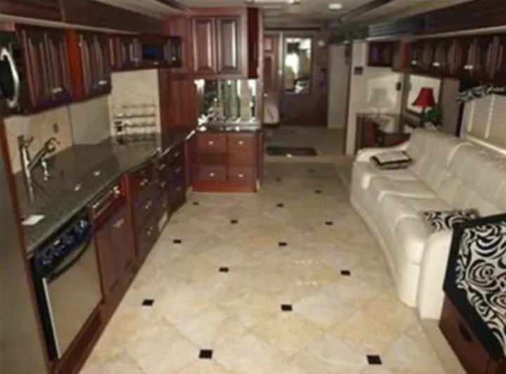 Experience luxury RV rental travel in this spacious interior, featuring a full kitchen with dark wood cabinetry and a comfortable white sofa.. Fleetwood Revolution