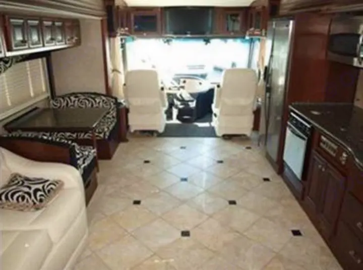 Spacious rv rental interior showing a full kitchen with dark cabinets, a dinette, and the driver's cockpit.. Fleetwood Revolution