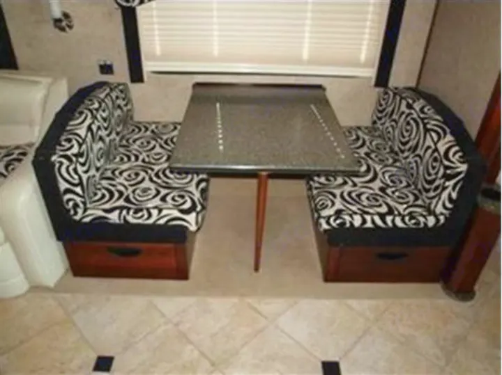 RV rental's cozy dinette with black & white patterned bench seats, table, and base storage compartments.. Fleetwood Revolution