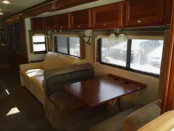 RV rental interior featuring a comfortable cream sofa, wooden dining booth, and overhead cabinets in the living space.. Winnebago Journey 2017