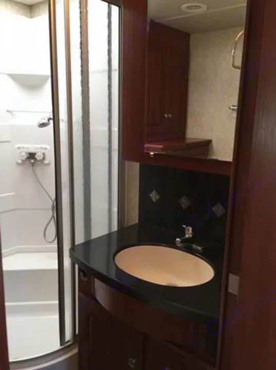 Well-appointed RV rental bathroom with shower, vanity sink, dark countertop, and built-in wood cabinetry for your trip.. Winnebago Journey 2017