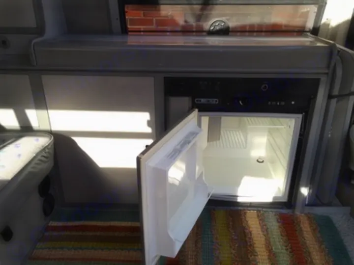 Inside an RV rental: View of the built-in fridge with its door open, ready for your camping provisions. Essential for comfort on the road.. Volkswagen Eurovan Full Camper 1997