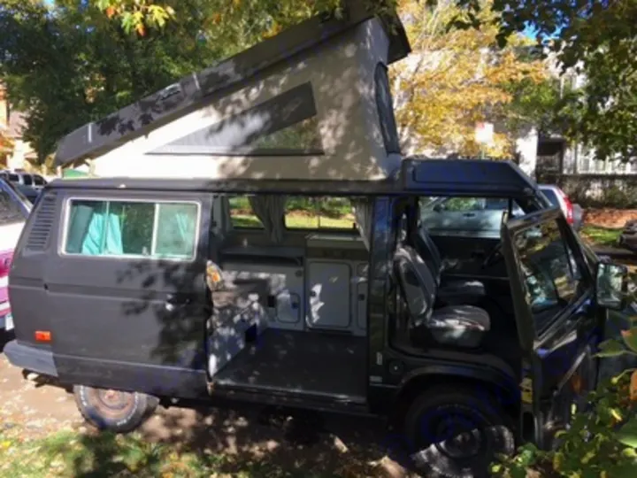Ready for adventure: a black pop-top camper van with open doors, showing its interior. An ideal RV rental for camping.. Volkswagen Vanagon Camper 1988