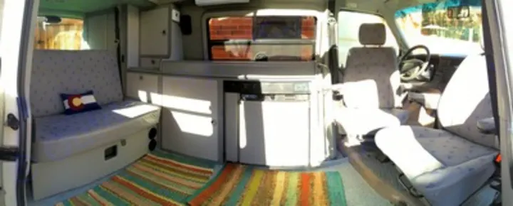 Inside a cozy camper van, ready for your next rv rental adventure. Features seating, kitchen, and bed area.. Volkswagen Eurovan Full Camper 2001