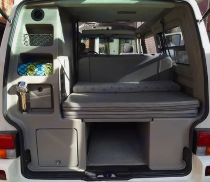 Compact RV rental interior: Rear view showing bed, storage, and outdoor shower access for your adventures.. Volkswagen Eurovan Full Camper 2001