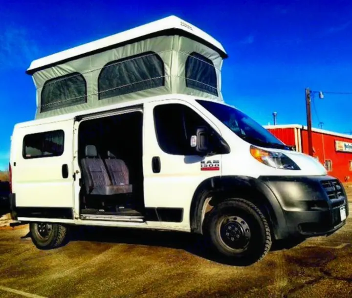 White Ram ProMaster camper van with an open side door and pop-top roof, suitable for an rv rental adventure.. Dodge Promaster 2017