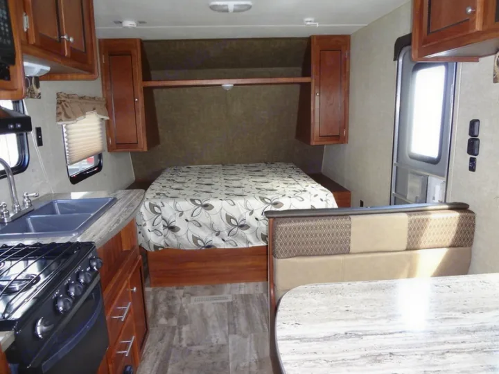 Bright and clean rv rental interior with kitchen, bed, and dining area. Ideal for road trips and camping.. Heartland Trail Runner 2017