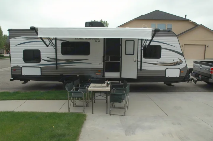 Setup for an RV rental adventure! A travel trailer with an extended awning and outdoor seating.. Heartland Trail Runner 2015
