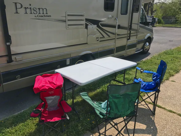 Coachmen Prism RV rental with a cozy outdoor setup: white table & three camping chairs for relaxing.. Coachmen Prism 2009