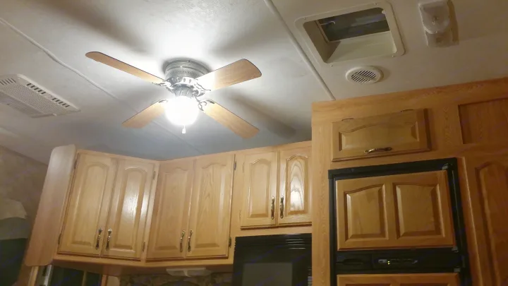 Inside an RV rental: Wood cabinets, a ceiling fan, and built-in appliances create a functional mobile kitchen.. Keystone Challenger 2005