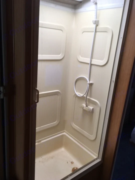 Compact RV rental shower interior with beige molded walls & white showerhead.. Fleetwood Other 2000