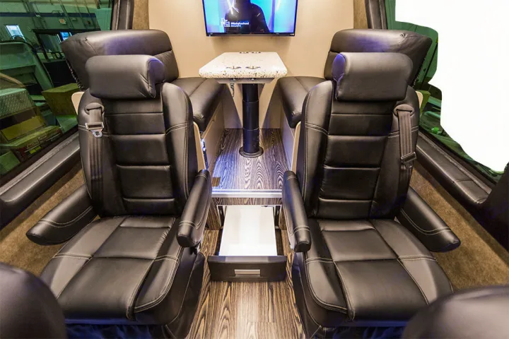 Experience luxury in this RV rental! Interior features two black leather captain's chairs, a central table, and TV for ultimate comfort.. Custom Coach Mauck2 2015