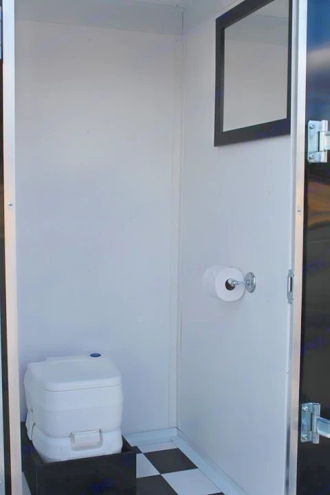A compact RV rental restroom with a white portable toilet on a checkerboard floor, mirror, and toilet paper.. Horton GameDay XL 2017