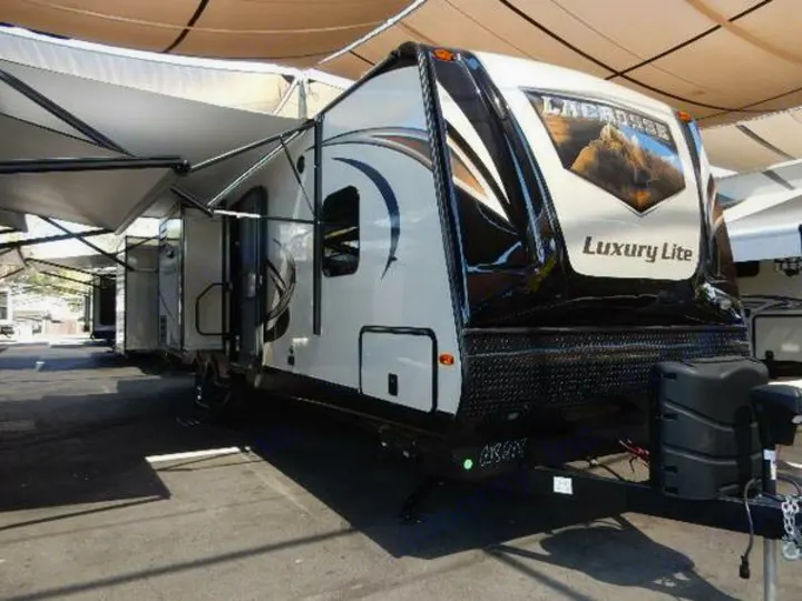 Exterior view of a white and black LaCrosse Luxury Lite travel trailer with extended awnings. Ideal for RV rental.. Prime Time Lacrosse 2017