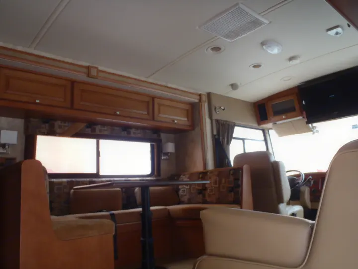 This RV rental interior features a comfortable dinette with patterned cushions, wooden cabinetry, and bright windows, ideal for travel.. Winnebago Sunstar 2012