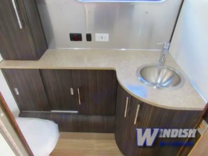 Clean, compact RV rental bathroom featuring a modern sink, counter, and dark wood-look cabinetry.. Airstream International Signature 25 2018
