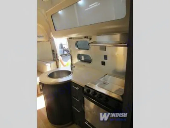 Modern RV rental kitchen with stainless steel sink, counter, and stove/oven, offering a compact and functional space.. Airstream International Signature 25 2018