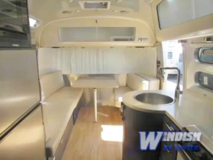 Spacious RV rental interior featuring a dinette, compact kitchen with sink, and refrigerator.. Airstream International Signature 25 2018