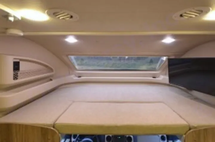 Cozy overcab sleeping area in this modern RV rental, featuring a bright skylight, comfortable bed, and TV.. Jayco Envoy 31L 2018