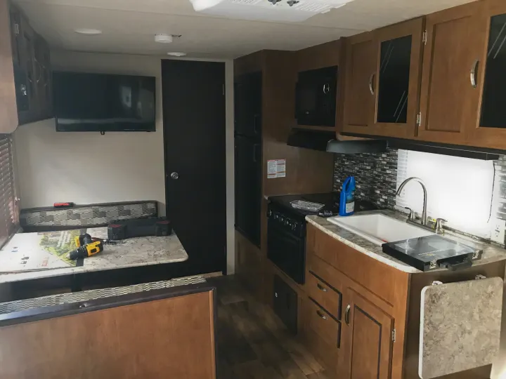 Inside this RV rental: a modern kitchen (sink, stove, microwave) and spacious dinette seating area.. Forest River Wildwood X-Lite 2018