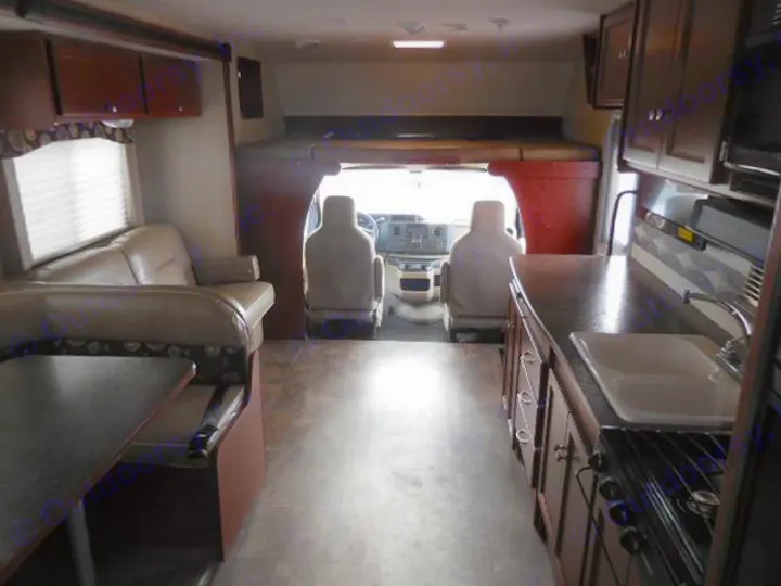 RV rental interior shows a spacious view of the kitchen, living area, and front cab with an overhead bunk.. Winnebago ITASCA 2014