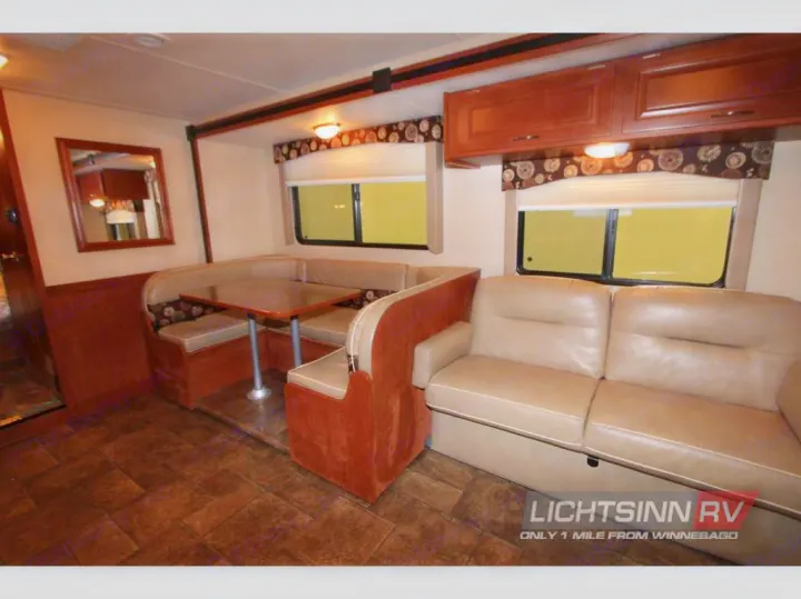 RV rental interior features a cozy dinette booth, sofa, and overhead cabinets for comfortable living on the road.. Winnebago ITASCA 2014